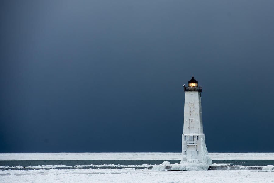 Lighthouse on snowy plain with dark blue sky background